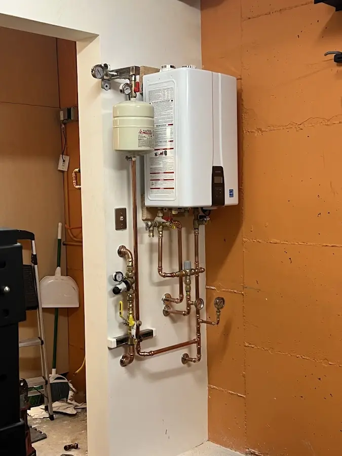 Plumbing technician inspecting water heater connections in Clinton